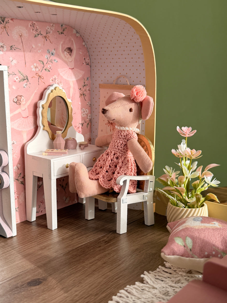 Ballerina mouse getting ready at the vanity table, with a potted flower and a swan poster on the wall