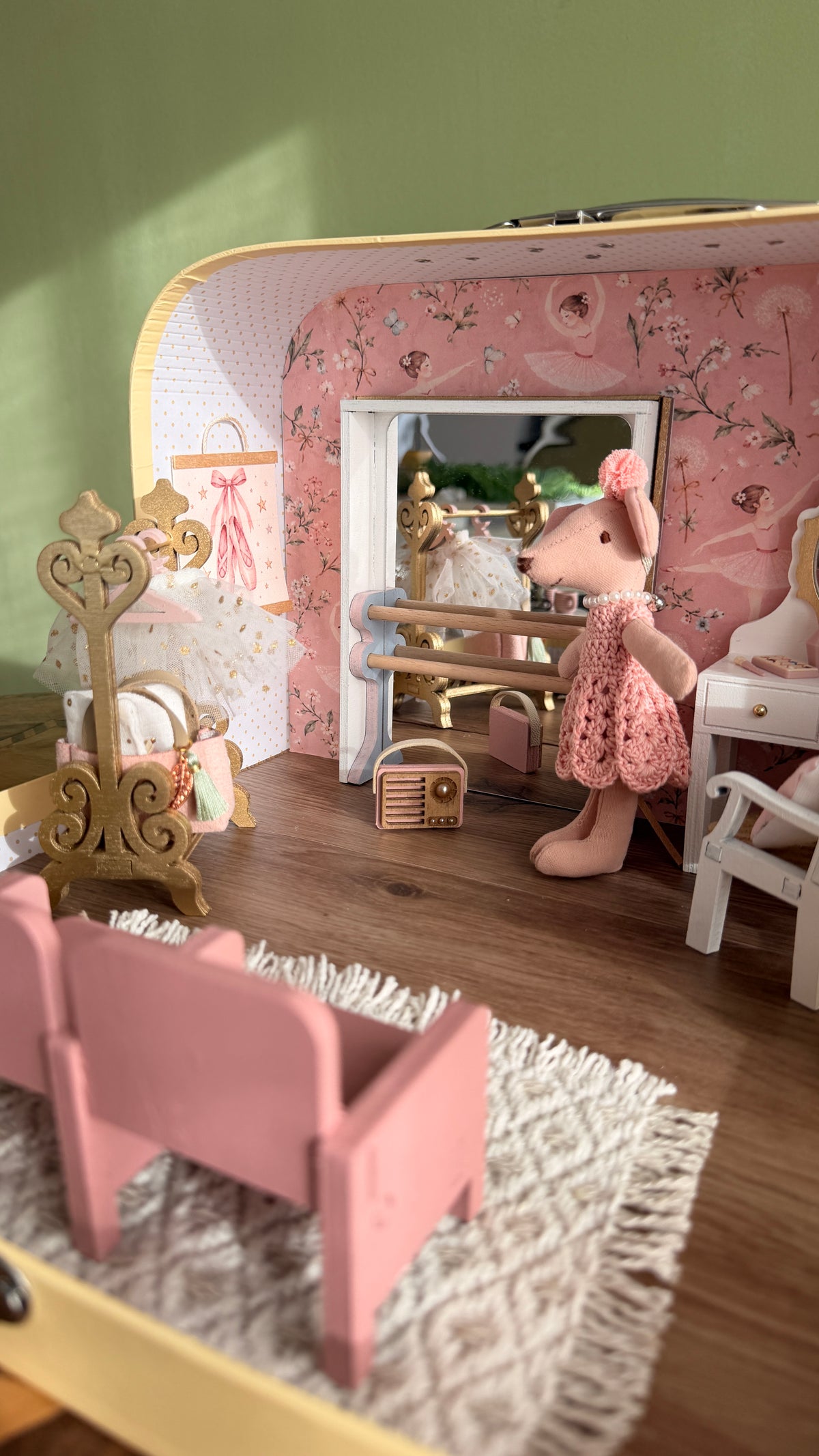 Inside the ballerina suitcase dollhouse: ballet barre with mirror, ballerina mouse, tutu on a gold stand and pink theatre seats