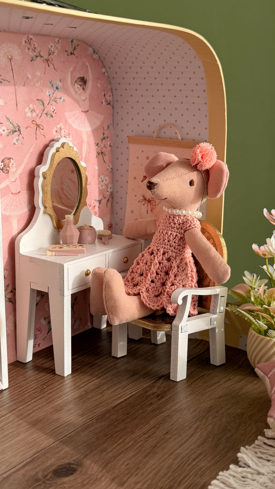 Ballerina mouse in a crocheted pink dress sitting at the white vanity table with gold mirror