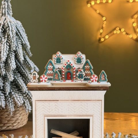 Miniature gingerbread house set with gingerbread figures, trees and candies on a dollhouse fireplace