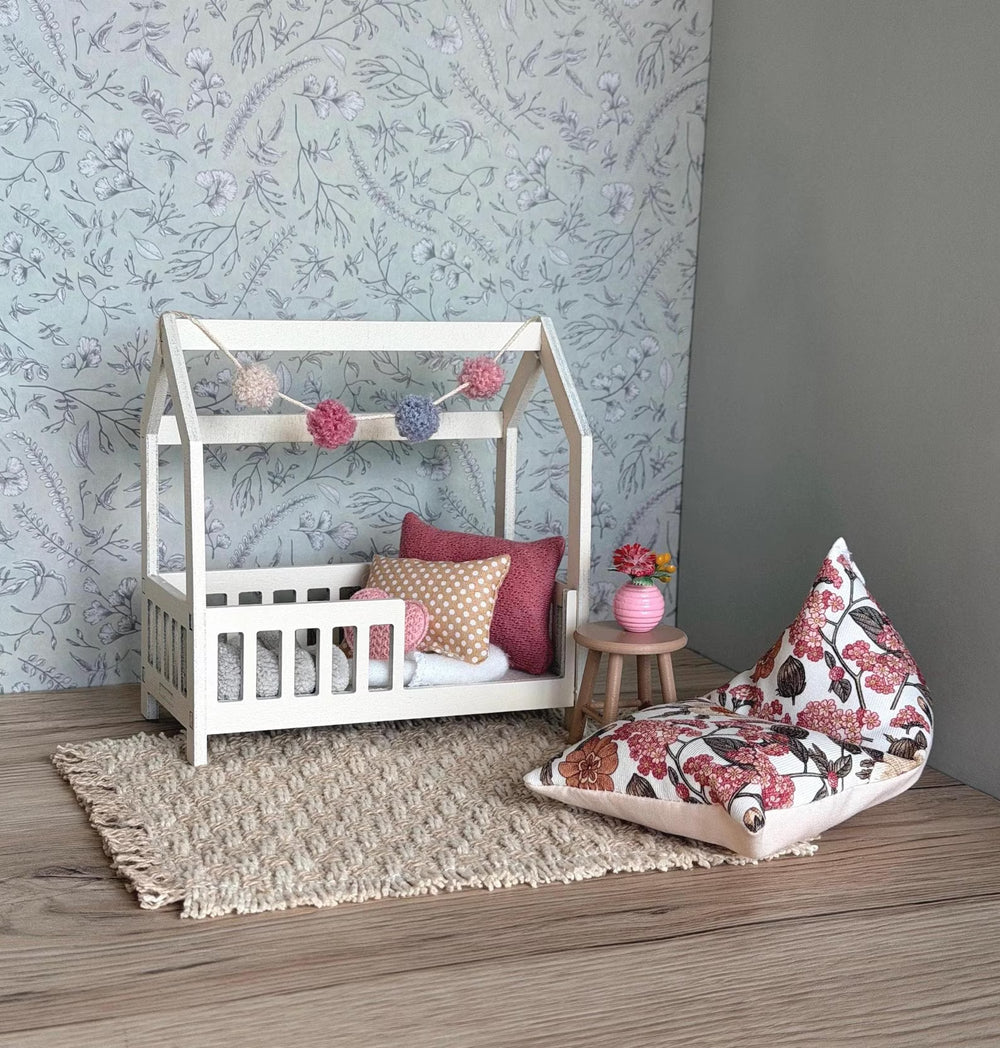 1:12 scale dollhouse kids bedroom with a white house bed, pom-pom garland, floral bean bag and woven rug