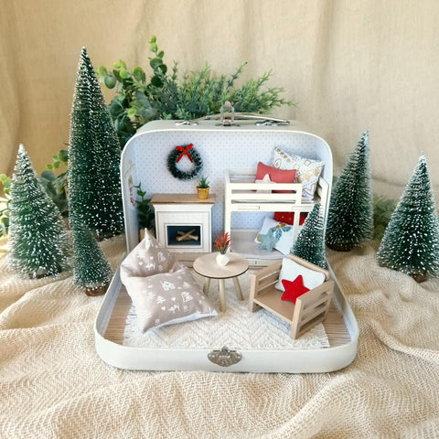 Christmas Joy small suitcase dollhouse with a tiny fireplace, wreath and bunk bed among miniature Christmas trees