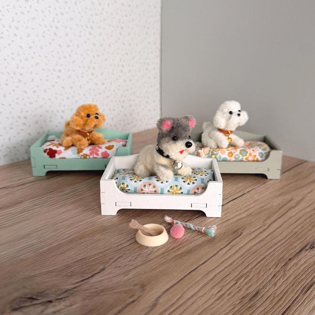 Tiny plush dog in a miniature wooden dog bed with floral cushion