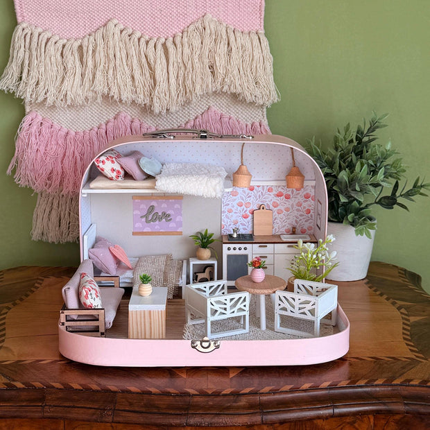 Blush Haven pink medium suitcase dollhouse with a loft bed, floral kitchen, round table and white chairs