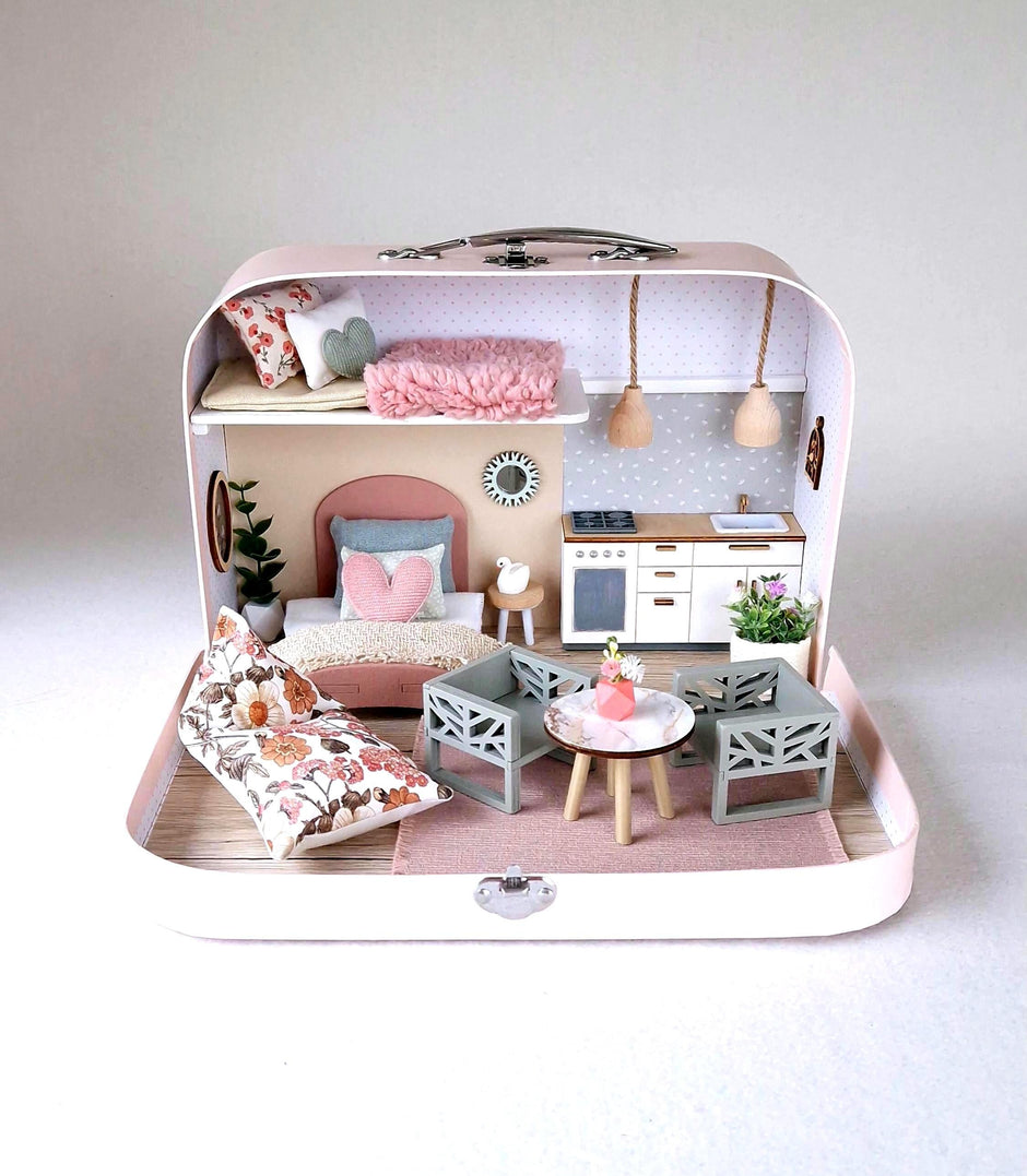 Spring Breeze medium suitcase dollhouse in pink with a floral bean bag, sage dining chairs and white kitchen