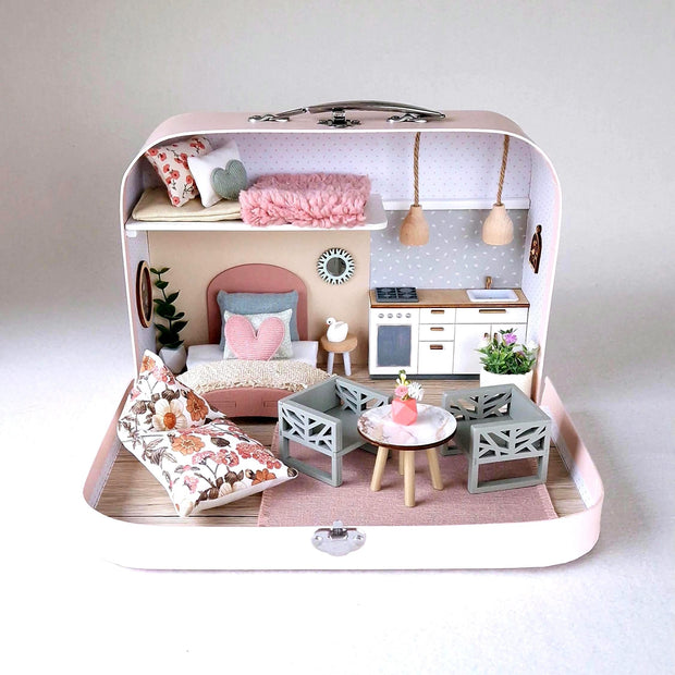 Spring Breeze medium suitcase dollhouse in pink with a floral bean bag, sage dining chairs and white kitchen